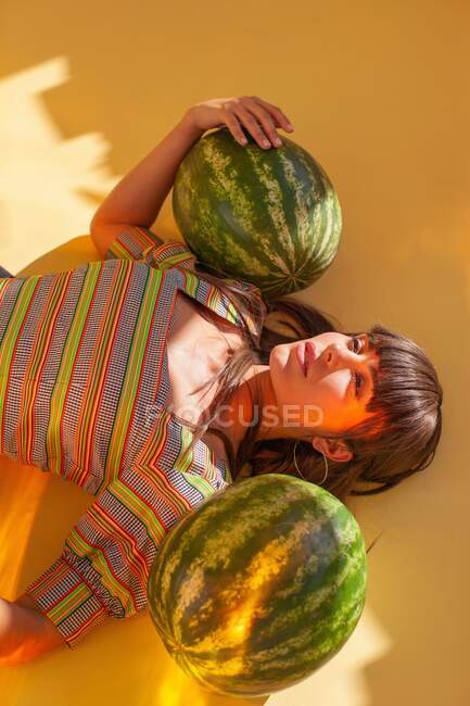 Mulher deitada no chão ao lado de duas melancias — Fotografia de Stock