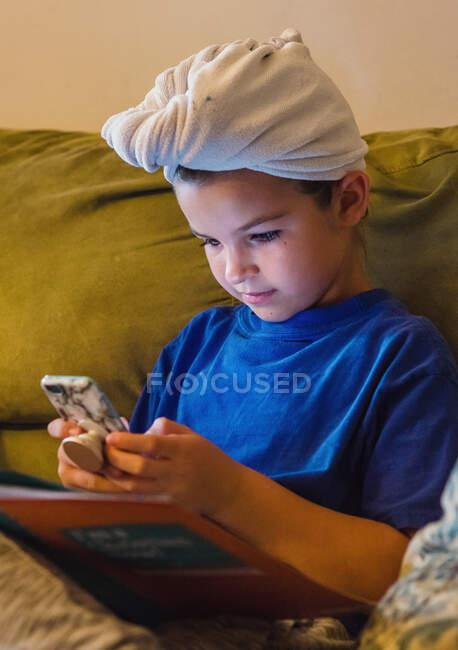 Ragazza con un asciugamano in testa guardando il suo cellulare — Foto stock