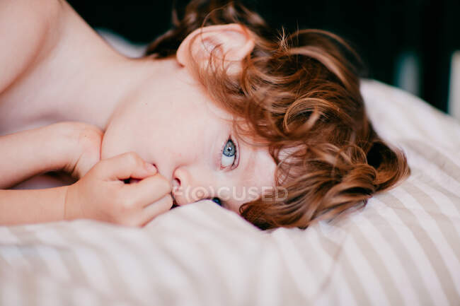 Портрет маленького рудого хлопчика, що лежить на ліжку — стокове фото