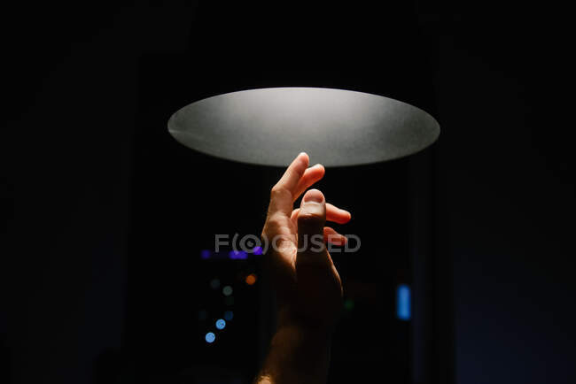 Mão do homem chegando em direção a uma luz de teto — Fotografia de Stock