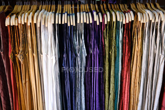 Vestidos multicolores colgando en un armario - foto de stock