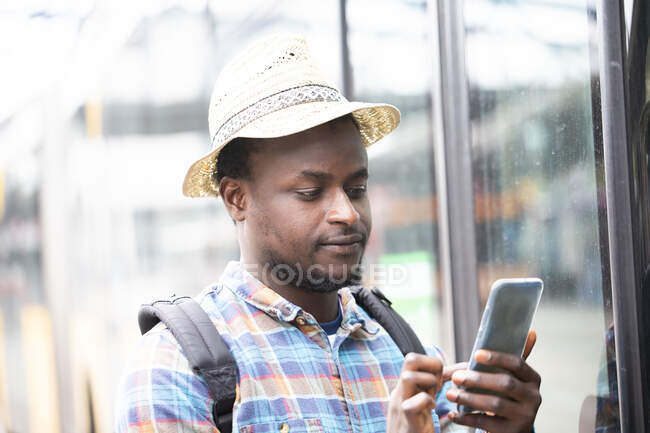 Portrait of a man standing by a bus using a mobile phone — Stock Photo