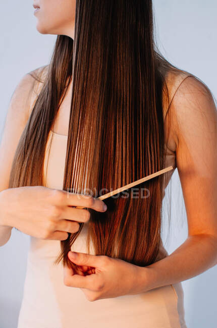 Primer plano de una mujer peinándose el pelo largo - foto de stock