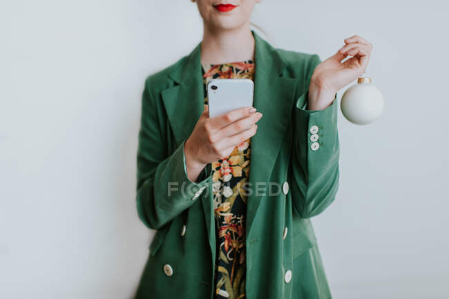 Woman holding christmas bauble and mobile phone — Stock Photo
