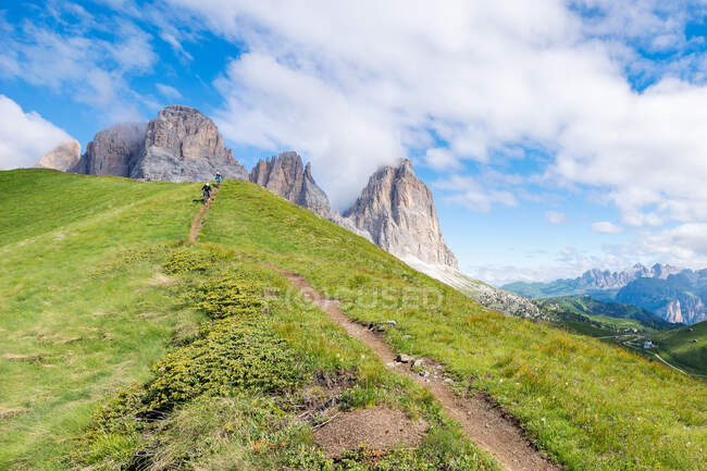 Dos personas en bicicleta de montaña por encima de Passo Sella, Val Gardena, Tirol del Sur, Italia - foto de stock