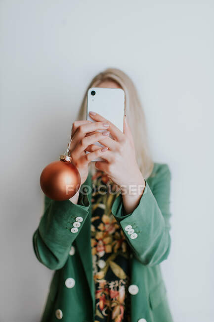 Frau hält Christbaumkugel in der Hand und macht Selfie — Stockfoto