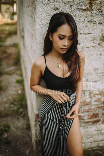 Elegante asiático jovem mulher de pé por idade tijolo parede — Fotografia de Stock