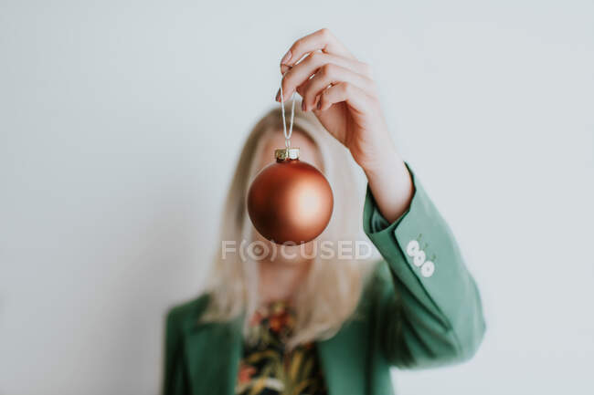 Женщина держит рождественскую безделушку перед лицом — стоковое фото