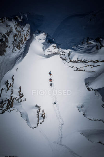 Четыре лыжника поднимаются по крутому склону в задней части горнолыжного курорта Гаштайн, Зальцбург, Австрия — стоковое фото