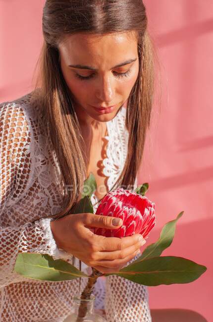 Woman sitting on a table touching a protea flower — Stock Photo