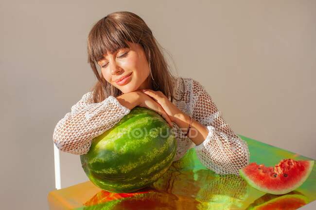 Smiling woman leaning on a watermelon daydreaming — Stock Photo