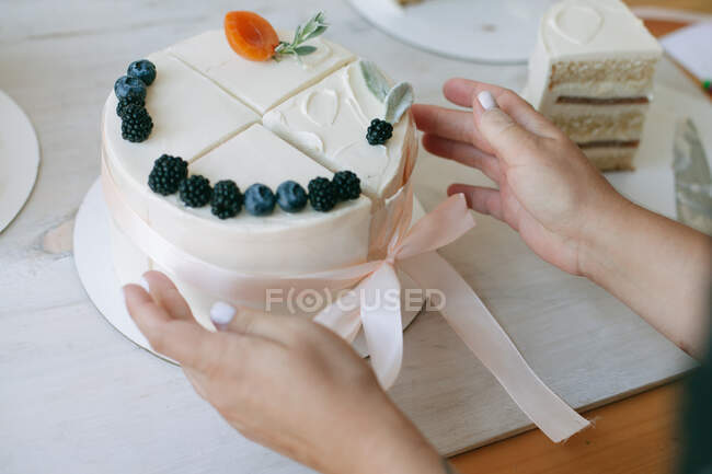 Woman putting together four slices of cake to make a compound cake — Stock Photo