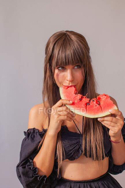 Retrato de una mujer comiendo una sandía - foto de stock