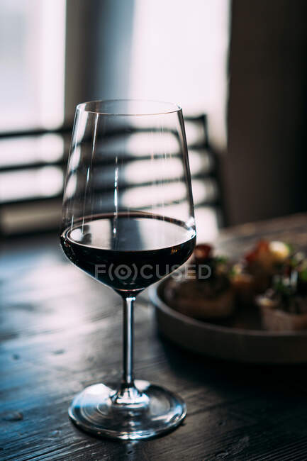 Copa de vino tinto junto a aperitivos - foto de stock
