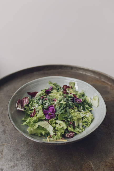 Миска зеленого салату з їстівними квітами на металевому підносі — стокове фото