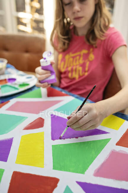 Girl sitting at a table painting — Stock Photo