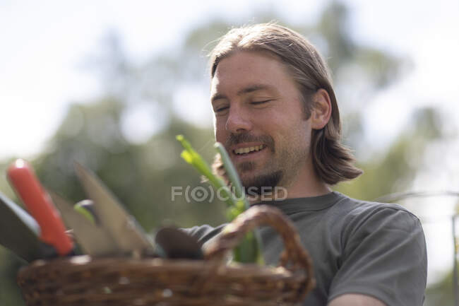 Portrait of a man carrying a basket filled with gardening equipment, Germany — Stock Photo