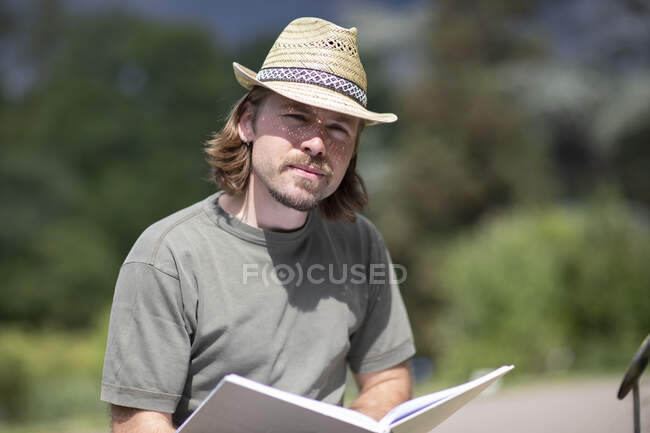 Portrait of a man sitting in a garden reading a book, Germany — Stock Photo
