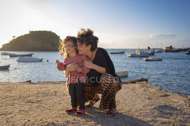 Donna sorridente che abbraccia la figlia sulla spiaggia, Armacao dos Buzios, Rio de Janeiro, Brasile, — Foto stock