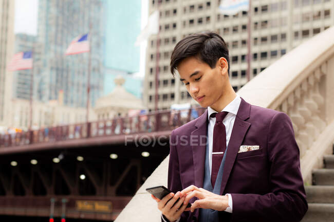 Junger Geschäftsmann am Flussufer mit Blick auf sein Handy, Chicago, Illinois, Vereinigte Staaten — Stockfoto