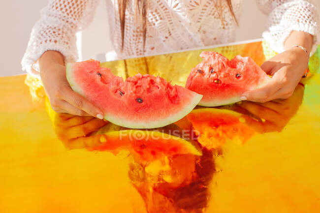 Woman holding slices of watermelon on holographic foil — Stock Photo