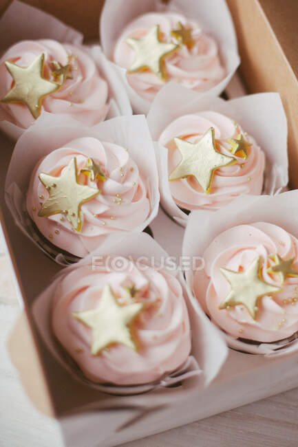Close-up of a box of cupcakes with gold colored decoration — Stock Photo