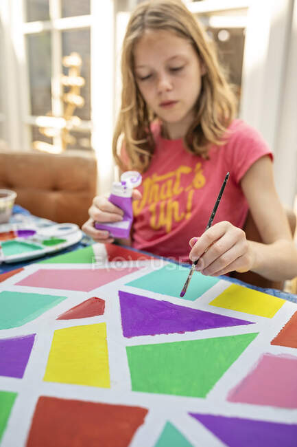 Chica sentada en una mesa de pintura - foto de stock