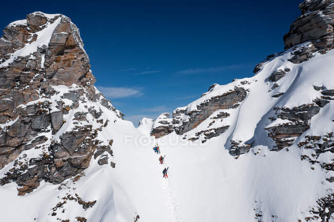 Три лыжника поднимаются по крутому склону в задней части горнолыжного курорта Гаштайн, Зальцбург, Австрия — стоковое фото