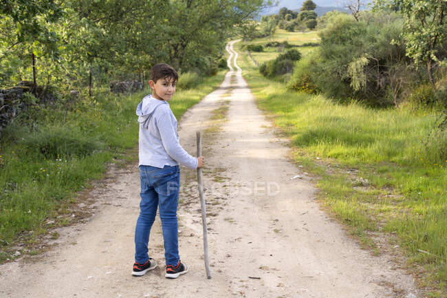 Menino em pé em um caminho de pedestre segurando um pau, Espanha — Fotografia de Stock