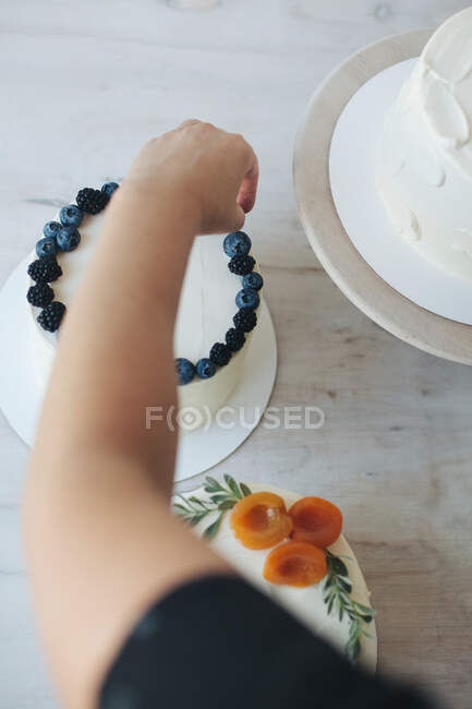 Frau dekoriert Kuchen mit Blaubeeren und Brombeeren — Stockfoto
