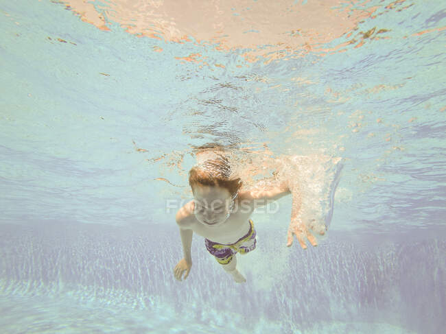 Ragazzo che nuota sott'acqua in piscina — Foto stock