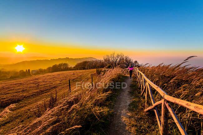 Femme marchant le long du sentier à la belle scène du coucher du soleil, Italie — Photo de stock