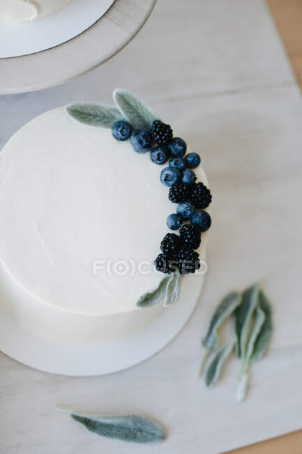 Cakes being decorated with buttercream icing and fruit — Stock Photo