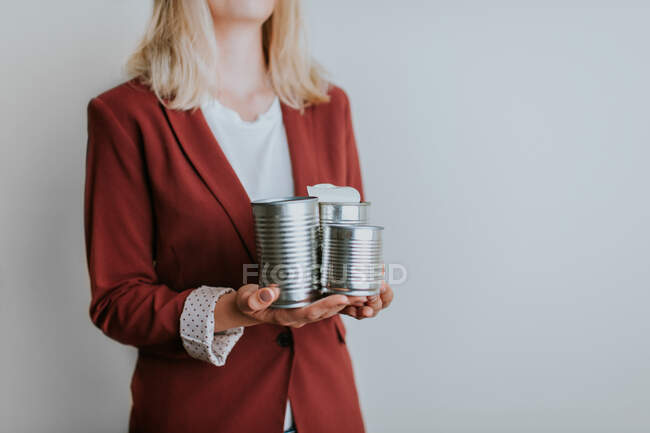 Woman holding three metal cans on white background — Stock Photo