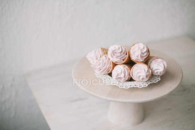 Coni di cialde ripieni di panna montata su una torta — Foto stock