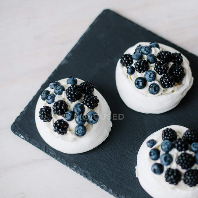 Overhead view of Pavlova desserts with blueberries and blackberries on slate — Stock Photo