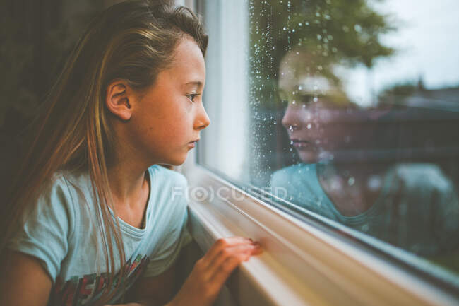 Chica mirando a través de una ventana de tren, Inglaterra, Reino Unido - foto de stock