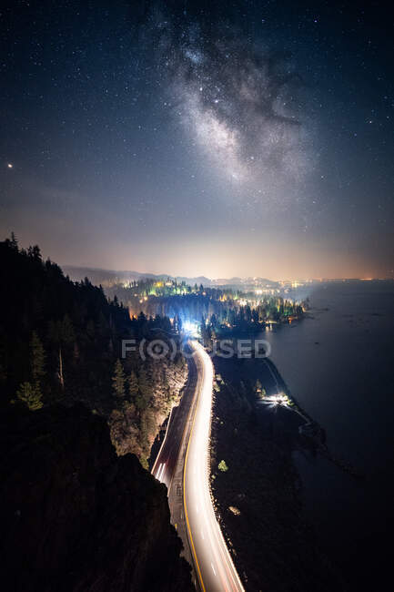 Milky Way above road and Distant City Lights, Cave Rock, Lake Tahoe, Nevada, États-Unis — Photo de stock