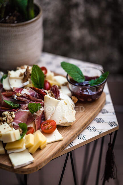 Charcuterie and cheese on a wooden chopping board — Stock Photo
