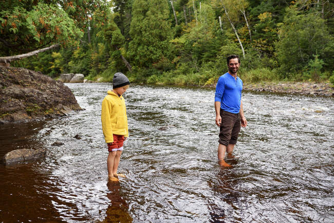 Padre e hijo de pie en un río, Estados Unidos - foto de stock