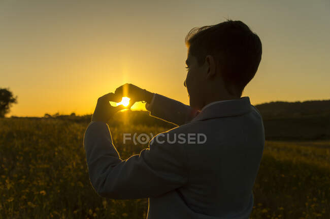 Boy making a heart shape with his hands at sunset, Spain — Stock Photo