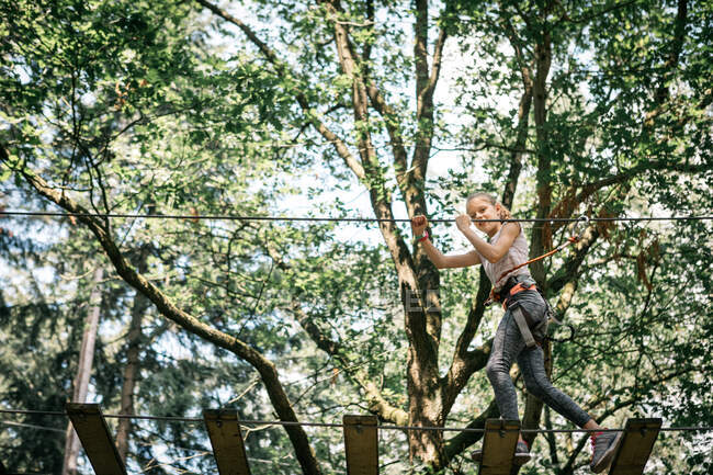 Menina jogando em um parque de aventura no topo da árvore — Fotografia de Stock