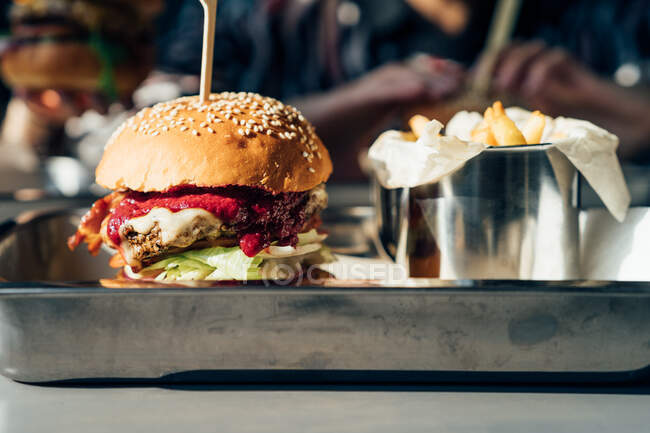 Cheeseburger with cranberry sauce and French fries on a tray — Stock Photo