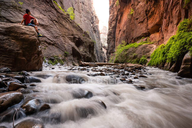 Hiker sitting on a Boulder in Slot Canyon, The Narrows, Zion National Park, Utah, United States — Foto stock