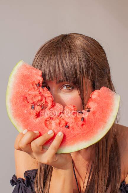 Woman hiding behind a slice of watermelon — Stock Photo
