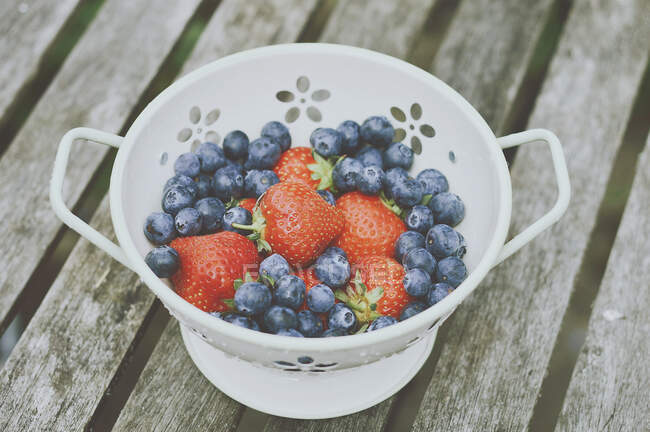 Strawberries and blueberries in a colander — Stock Photo