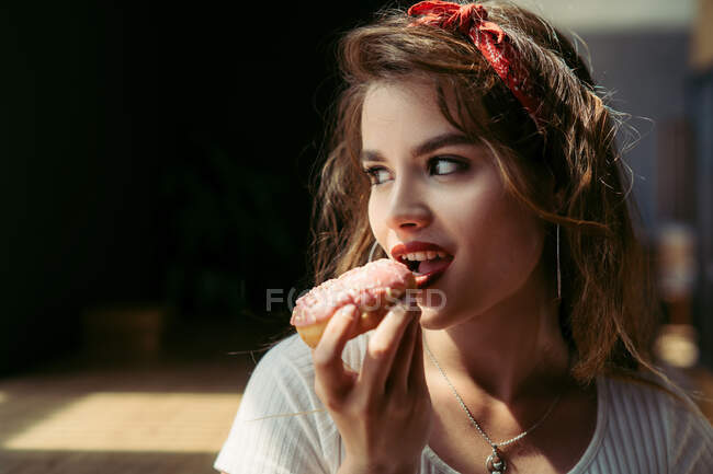 Портрет сексуальной молодой женщины, поедающей пончик — стоковое фото