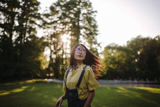 Retrato de una mujer parada en el parque sacudiéndose el pelo, Serbia - foto de stock