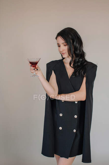 Mulher de smoking vestido segurando vidro com coquetel — Fotografia de Stock