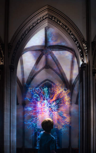 Boy looking at a flash of light coming from a stained glass window in a cathedral — Stock Photo